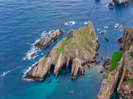 Aerial view of the rugged rocky islets and turquoise waters near Silence Beach Viewpoint with steep cliffs and lush green vegetation Cudillero Asturias Spain.