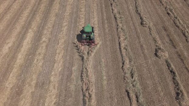 Aerial view of a tractor raking hay in a field South Africa. Aerial view of a tractor raking hay in a field South Africa.