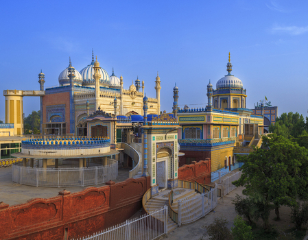 View of Jamia Masjid Bhong Sharif featuring intricate architectural details colorful domes and decorative walls under a clear blue sky in Bhong Punjab Pakistan.