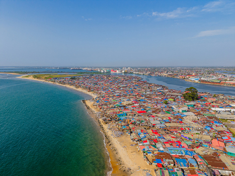 Aerial view of a sprawling settlement where vibrant rooftops meet the tranquil ocean divided by a thin strip of sandy beach Monrovia Liberia.