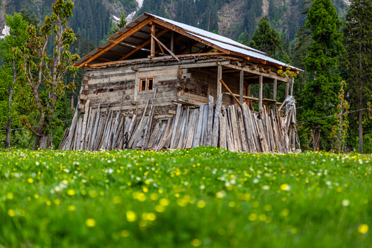 View of a traditional wooden cabin nestled in a lush green meadow with wildflowers and tall pine trees in Arang Kel Azad Kashmir Pakistan. View of a traditional wooden cabin nestled in a lush green meadow with wildflowers and tall pine trees in Arang Kel Azad Kashmir Pakistan.