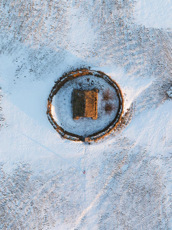 Aerial view of Grafarkirkja a historic turf roofed church surrounded by a circular stone wall in a snow covered landscape in Hofsos Skagafjordur Iceland. Aerial view of Grafarkirkja a historic turf roofed church surrounded by a circular stone wall in a snow covered landscape in Hofsos Skagafjordur Iceland.