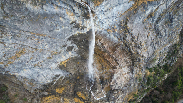 Aerial view of a cascade of water gracefully descends from a rugged cliff face carving a path through the textured rock Sallanches Auvergne Rhône Alpes France. Aerial view of a cascade of water gracefully descends from a rugged cliff face carving a path through the textured rock Sallanches Auvergne Rhône Alpes France.