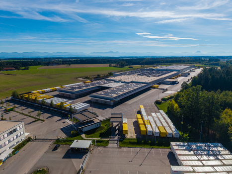 Aerial view of Logistikzentrum Allhaming featuring large warehouse buildings with solar panels loading docks and rows of shipping containers in Allhaming Oberosterreich Austria. Aerial view of Logistikzentrum Allhaming featuring large warehouse buildings with solar panels loading docks and rows of shipping containers in Allhaming Oberosterreich Austria.