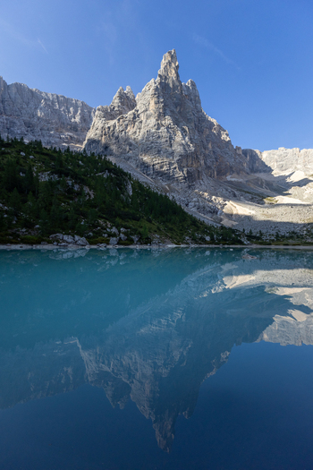 View of Lake Sorapis with its turquoise water reflecting the jagged peaks of the Dolomites under a clear blue sky in Cortina d Ampezzo Veneto Italy.