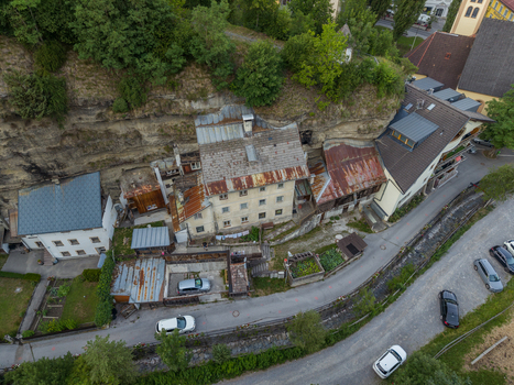 Aerial view of historic rock cut houses built into the cliffside in the alpine town of Imst featuring rustic rooftops and stone walls in Imst Tyrol Austria.