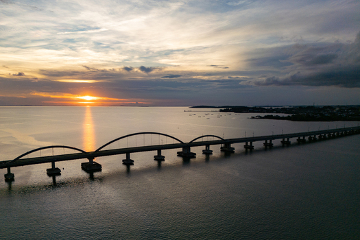 Aerial view of Dompak Bridge with its distinctive arches over the calm sea during a golden sunset in Tanjung Pinang Riau Islands Indonesia. Aerial view of Dompak Bridge with its distinctive arches over the calm sea during a golden sunset in Tanjung Pinang Riau Islands Indonesia.