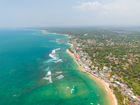 Aerial view of the turquoise coastline with white waves crashing on the sandy beach and lush tropical greenery Hikkaduwa Southern Province Sri Lanka. Aerial view of the turquoise coastline with white waves crashing on the sandy beach and lush tropical greenery Hikkaduwa Southern Province Sri Lanka.