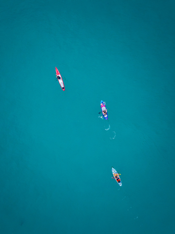 Aerial view of three people paddling on stand up paddleboards in the clear turquoise water of Vietnam. Aerial view of three people paddling on stand up paddleboards in the clear turquoise water of Vietnam.