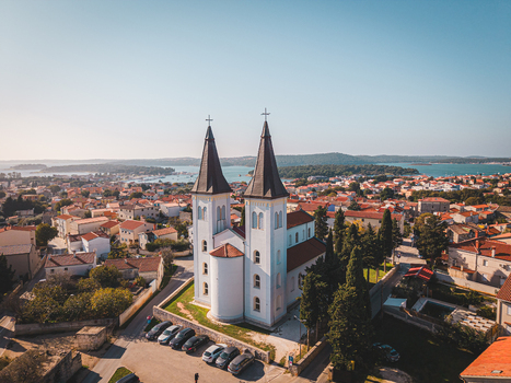 Aerial view of the striking white facade of the Church of Our Lady of the Sea sharply contrasts against the terracotta rooftops Medulin Istria County Croatia.