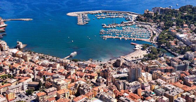 Aerial view of the vibrant harbor and historic town center with colorful buildings and numerous yachts moored in the blue sea at Rapallo Liguria Italy. Aerial view of the vibrant harbor and historic town center with colorful buildings and numerous yachts moored in the blue sea at Rapallo Liguria Italy.
