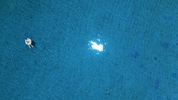 Aerial view of a person floating in blue water in Honduras. Aerial view of a person floating in blue water in Honduras.