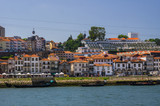 Aerial view of the red tiled roofs cascade down to the Douro River where boats bob gently framed by the iconic cable cars against a clear sky Porto Porto District Portugal. Aerial view of the red tiled roofs cascade down to the Douro River where boats bob gently framed by the iconic cable cars against a clear sky Porto Porto District Portugal.