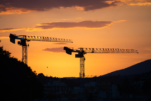 View of two construction cranes silhouetted against a vibrant orange sunset sky in Nice Provence Alpes Cote d Azur France. View of two construction cranes silhouetted against a vibrant orange sunset sky in Nice Provence Alpes Cote d Azur France.