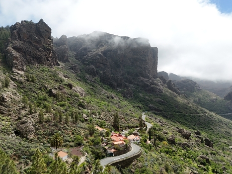 Aerial view of Roque Nublo s majestic cliffs embrace a winding road and quaint houses nestled amidst lush greenery under a soft ethereal mist La Culata Canarias Spain. Aerial view of Roque Nublo s majestic cliffs embrace a winding road and quaint houses nestled amidst lush greenery under a soft ethereal mist La Culata Canarias Spain.