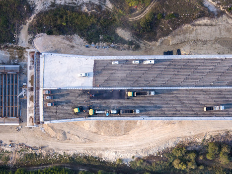 Aerial view of a bridge construction site with workers construction vehicles and asphalt paving equipment on the deck in Istanbul Istanbul Turkiye.
