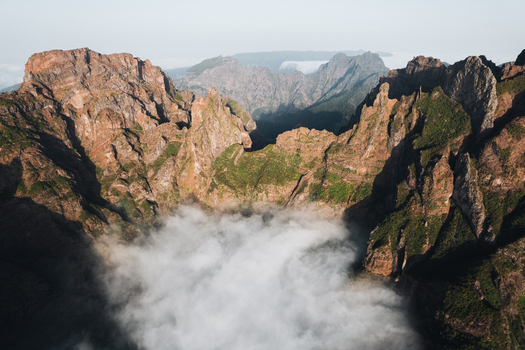 Aerial view of rugged mountain peaks piercing through a sea of ethereal clouds Pico do Areeiro Madeira Portugal.