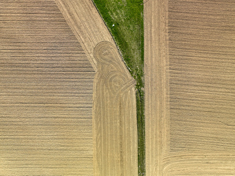 Aerial view of plowed agricultural fields with geometric patterns and a green grassy strip in Borgo d Ale Piedmont Italy.