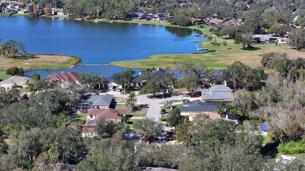 Aerial view of a residential neighborhood with houses lush trees and a calm lake in Plant City Florida United States.