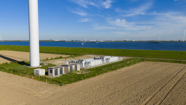 Aerial view of a large wind turbine base and a battery energy storage system next to a river under a clear blue sky in Ooltgensplaat Zuid Holland Netherlands. Aerial view of a large wind turbine base and a battery energy storage system next to a river under a clear blue sky in Ooltgensplaat Zuid Holland Netherlands.