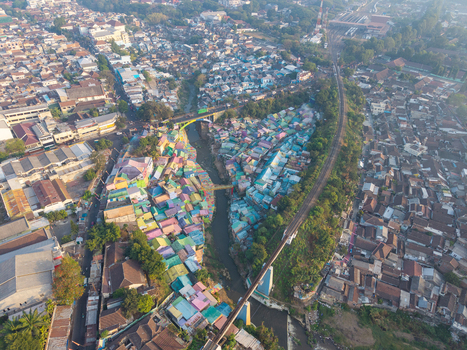 Aerial view of Jodipan Colorful Village with vibrant houses along the river and a railway bridge in Malang East Java Indonesia.