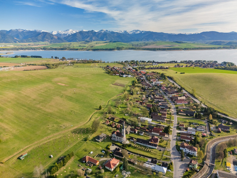 Aerial view of Liptovsky Trnovec village with its church tower green fields and Liptovska Mara reservoir under the Tatra Mountains Liptovsky Trnovec Zilina Region Slovakia.