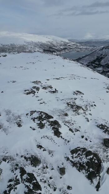 Aerial view of people on the snowy Kvaloya mountain ridge Norway.