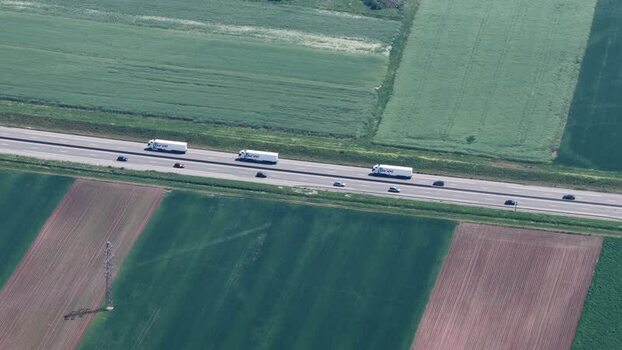 Aerial view of trucks driving on a highway through fields France.