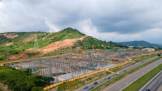 Aerial view of TCN SubStation Katampe with electrical infrastructure transmission towers and power lines near a hilly landscape and highway in Abuja Federal Capital Territory Nigeria.
