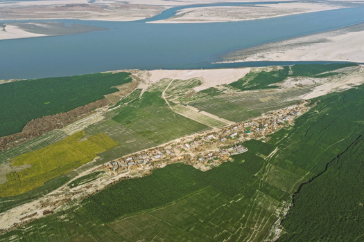Aerial view of a rural village nestled between lush green agricultural fields and a wide river with sandy banks in Joypurhat Rajshahi Division Bangladesh. Aerial view of a rural village nestled between lush green agricultural fields and a wide river with sandy banks in Joypurhat Rajshahi Division Bangladesh.