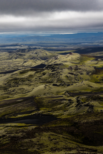 View of moss covered volcanic landscapes stretching under a vast cloudy sky a textured terrain in shades of green and dark brown Skaftárhreppur Skaftárhreppur Iceland. View of moss covered volcanic landscapes stretching under a vast cloudy sky a textured terrain in shades of green and dark brown Skaftárhreppur Skaftárhreppur Iceland.