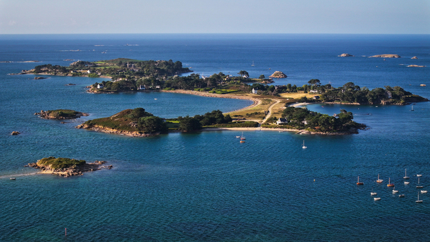 Aerial view of Callot island with sandy beaches and scattered houses where the deep blue sea meets the shore Carantec France.