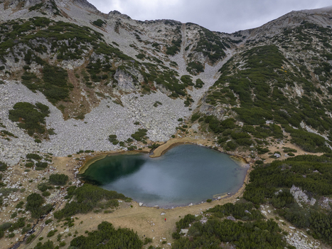 Aerial view of Muratovo Lake in Pirin National Park surrounded by rocky mountain slopes and green vegetation in Blagoevgrad Province Bulgaria. Aerial view of Muratovo Lake in Pirin National Park surrounded by rocky mountain slopes and green vegetation in Blagoevgrad Province Bulgaria.