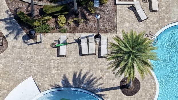 Aerial view of the swimming pool area at Windward Ranch Boulevard featuring lounge chairs a palm tree and paved pool deck in St. Johns County Florida United States. Aerial view of the swimming pool area at Windward Ranch Boulevard featuring lounge chairs a palm tree and paved pool deck in St. Johns County Florida United States.
