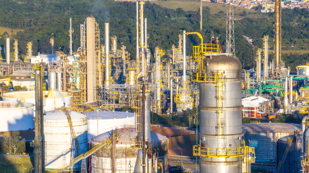 Aerial view of the petrochemical complex featuring tall industrial towers storage tanks and piping systems set against dense green vegetation in Santo Andre State of Sao Paulo Brazil.