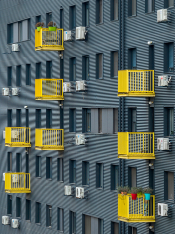 Aerial view of a modern building facade featuring dark grey corrugated metal cladding bright yellow balconies and numerous air conditioning units in Belgrade City of Belgrade Serbia. Aerial view of a modern building facade featuring dark grey corrugated metal cladding bright yellow balconies and numerous air conditioning units in Belgrade City of Belgrade Serbia.