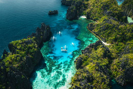 Aerial view of Big Lagoon with turquoise waters limestone cliffs and outrigger boats El Nido Bay Philippines. Aerial view of Big Lagoon with turquoise waters limestone cliffs and outrigger boats El Nido Bay Philippines.