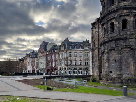 View of the historic Porta Nigra Roman city gate with surrounding traditional architecture under a cloudy sky in Trier Rheinland Pfalz Germany.
