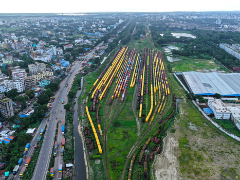 Aerial view of a large railway yard with numerous freight train cars lined up on parallel tracks next to a busy road and urban buildings in Chittagong Chittagong Division Bangladesh.