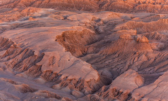 Aerial view of the rugged arid landscape of the Valley of the Moon with deep canyons and reddish brown rock formations in San Pedro de Atacama Antofagasta Chile.
