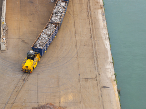 Aerial view of a yellow shunter locomotive pulling containers filled with scrap metal along the quay at Haven Genk Genk Vlaanderen Belgium. Aerial view of a yellow shunter locomotive pulling containers filled with scrap metal along the quay at Haven Genk Genk Vlaanderen Belgium.