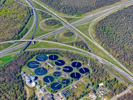 Aerial view of the wastewater treatment plant nestled amidst the verdant landscape contrasted by the intricate highway interchange above Sausheim Grand Est France.