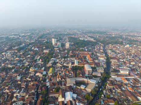 Aerial view of the dense urban landscape with its terracotta rooftops winding streets and hazy atmosphere in Malang East Java Indonesia.
