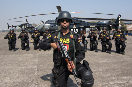 Dhaka Bangladesh 19 January 2017 View of RAB officers in black uniforms holding rifles while kneeling in front of a black helicopter at the RAB Headquarters. Dhaka Bangladesh 19 January 2017 View of RAB officers in black uniforms holding rifles while kneeling in front of a black helicopter at the RAB Headquarters.