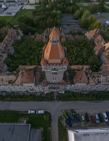 Aerial view of Hajmasker Barracks with its prominent central tower weathered orange tiled roofs and overgrown inner courtyard surrounded by trees in Hajmasker Hungary. Aerial view of Hajmasker Barracks with its prominent central tower weathered orange tiled roofs and overgrown inner courtyard surrounded by trees in Hajmasker Hungary.