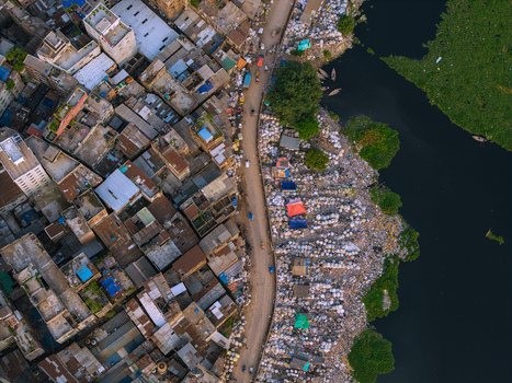 Aerial view of the Buriganga River flowing past dense urban housing and a riverside market with white sacks in Keraniganj Dhaka Division Bangladesh. Aerial view of the Buriganga River flowing past dense urban housing and a riverside market with white sacks in Keraniganj Dhaka Division Bangladesh.
