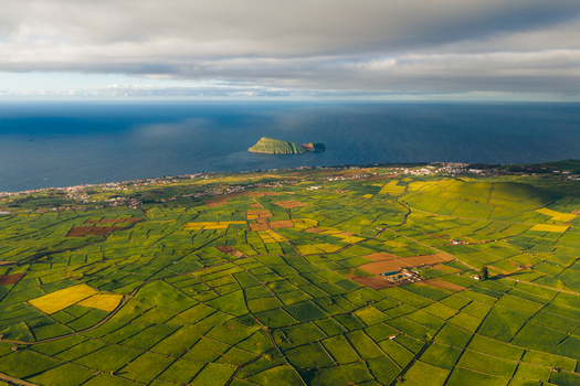 Aerial view of Pico Dona Joana volcanic cone and lush green patchwork fields overlooking the Atlantic Ocean and Ilheu de Cabras Feteira Acores Portugal. Aerial view of Pico Dona Joana volcanic cone and lush green patchwork fields overlooking the Atlantic Ocean and Ilheu de Cabras Feteira Acores Portugal.