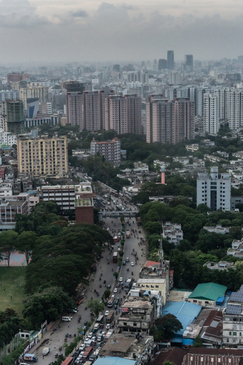 Dhaka Bangladesh 30 June 2025 Aerial view of the dense urban landscape of Dhaka featuring high rise residential buildings bustling streets with traffic and lush green trees.