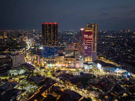 Surabaya Indonesia 28 August 2026 Aerial view of the illuminated city skyline at night featuring modern skyscrapers dense urban development and glowing street lights.
