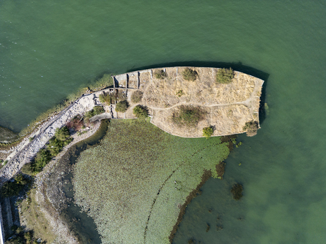 Aerial view of Mola e madhe a historic stone pier extending into the green waters of Lake Shkoder with dry vegetation and rocky paths in Shiroka Shkoder County Albania. Aerial view of Mola e madhe a historic stone pier extending into the green waters of Lake Shkoder with dry vegetation and rocky paths in Shiroka Shkoder County Albania.